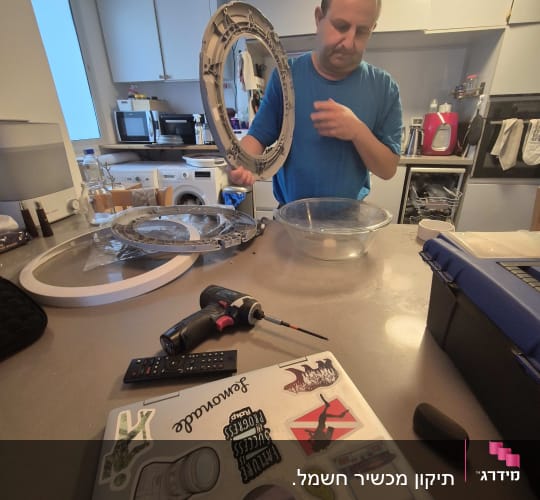 אדם עובד עם כלי עבודה במטבח, כולל מברגה ומחשב נייד